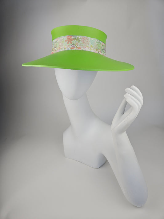 A neon green visor hat with a pastel floral band displayed on a white mannequin head.