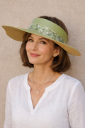 Woman wearing a white shirt and green visor against a beige background