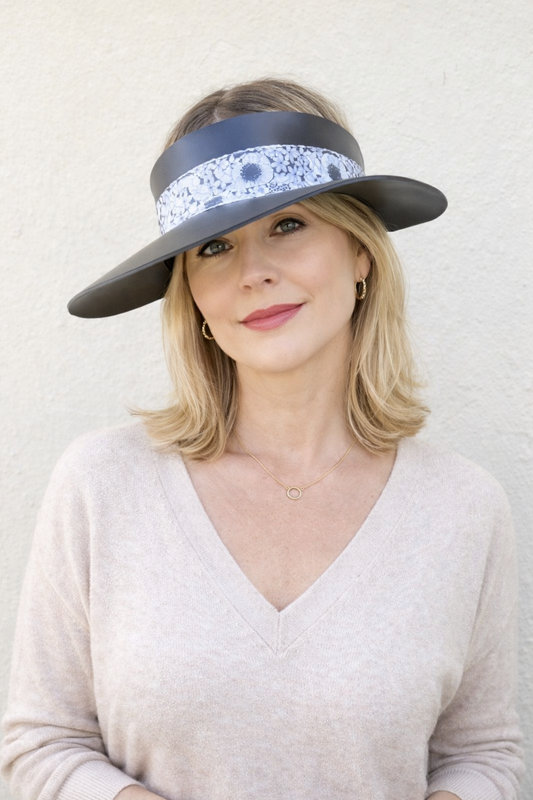 Woman wearing a wide-brimmed hat with a decorative band against a plain background