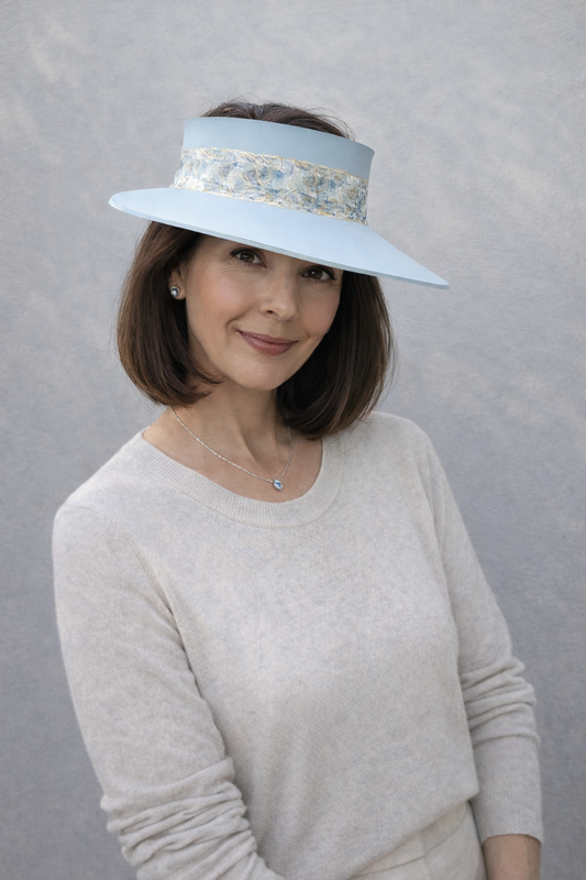 Woman wearing a light blue visor hat against a gray background