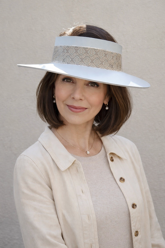 Woman wearing a wide-brimmed hat with a decorative band against a plain background