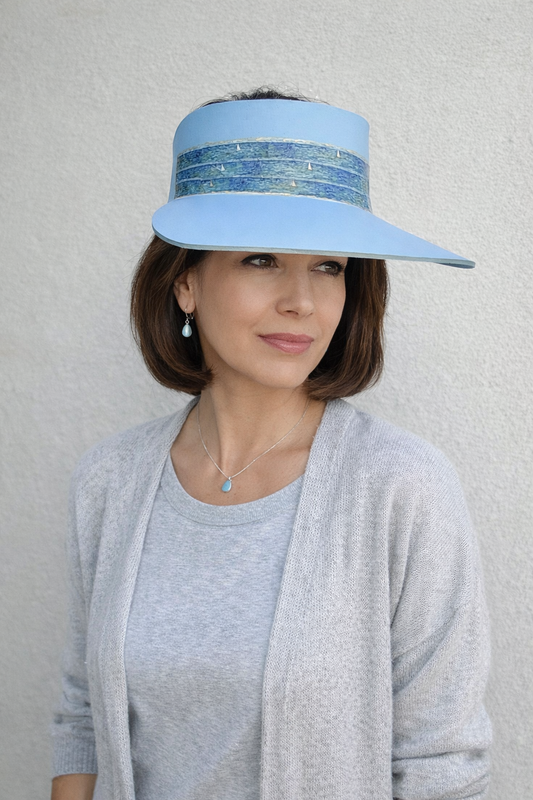 Woman wearing a light blue visor with a decorative band against a neutral background