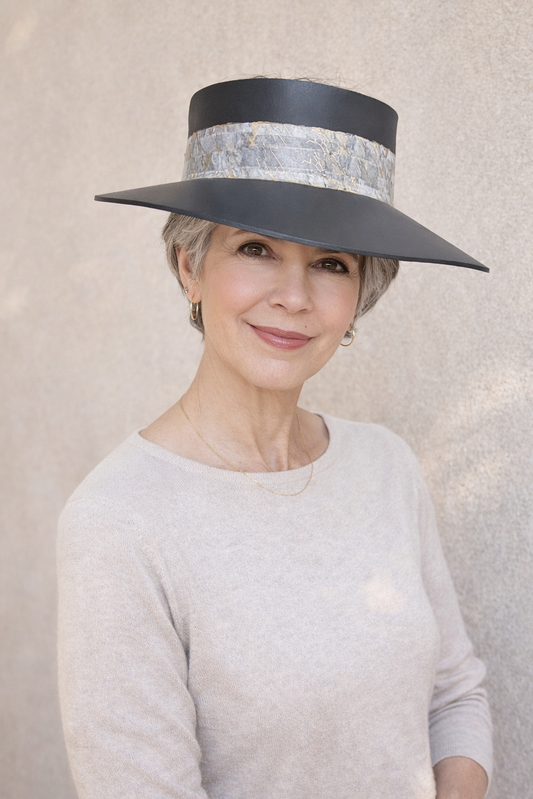 Woman wearing a wide-brimmed hat with a decorative band against a neutral background