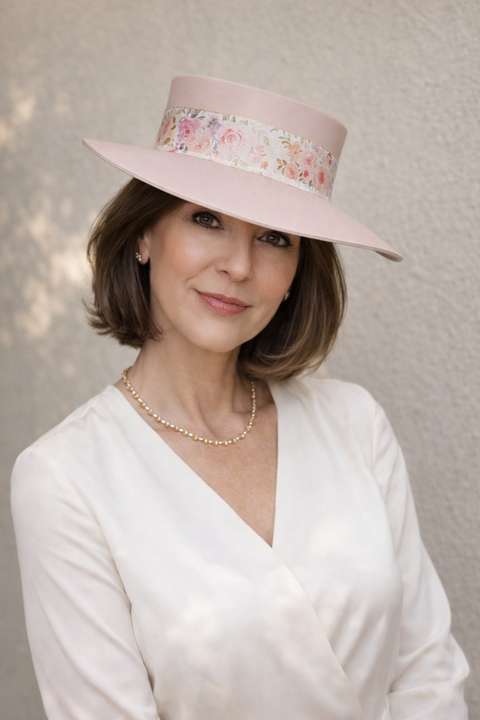 Woman wearing a pink hat with floral band against a neutral background