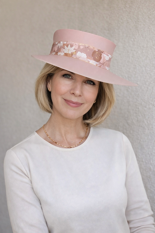 Woman wearing a pink hat with floral details against a plain background