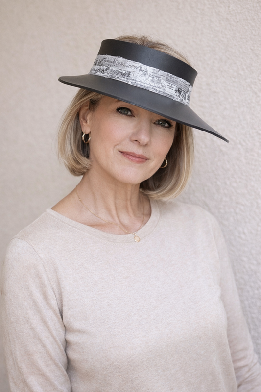 Woman wearing a wide-brimmed hat with decorative band against a neutral background