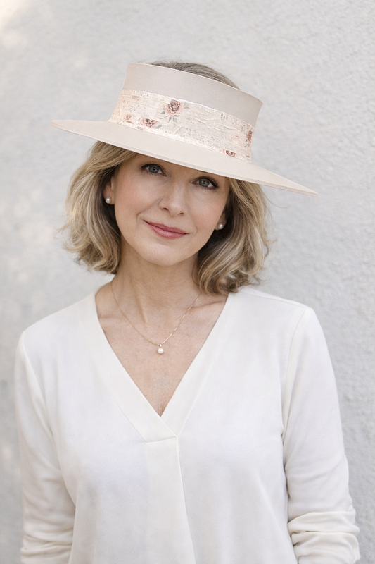 Woman wearing a beige hat with floral details against a light gray background