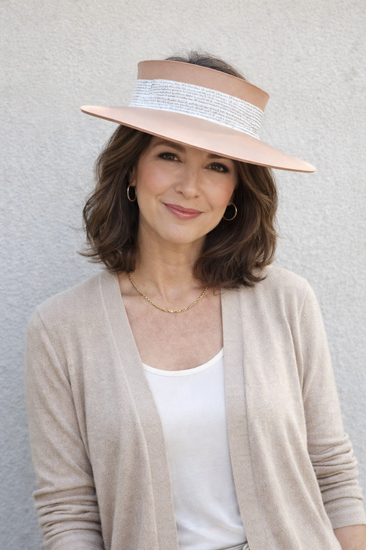 Woman wearing a beige visor hat against a gray background