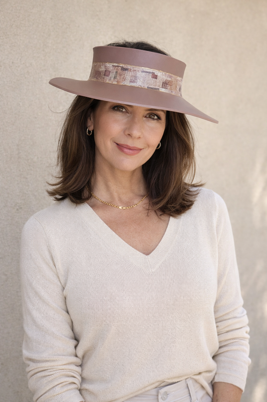 Woman wearing a wide-brimmed hat with a patterned band against a neutral background