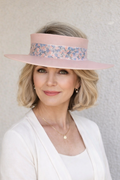 Woman wearing a pink visor with floral band against a plain background
