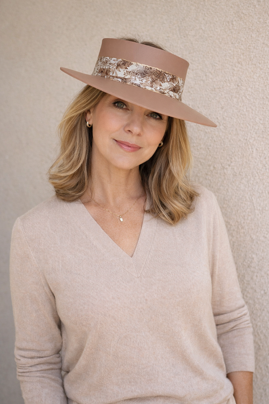 Woman wearing a beige hat with floral band against a neutral background