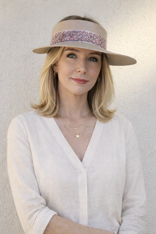 Woman wearing a beige visor with a pink band against a light background