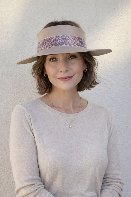 Woman wearing a wide-brimmed hat with a decorative band against a plain background