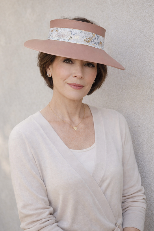 Woman wearing a wide-brimmed hat with floral band against a neutral background