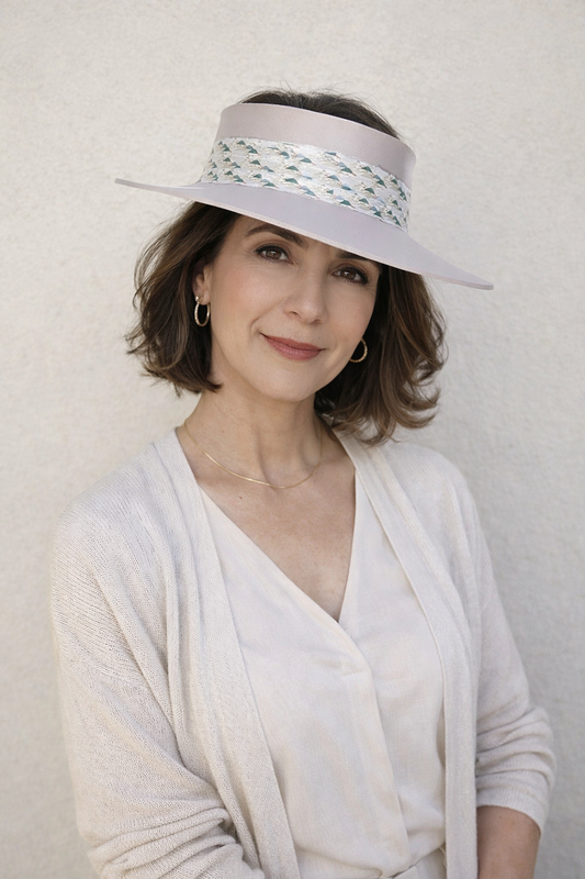 Woman wearing a white visor and light clothing against a plain background