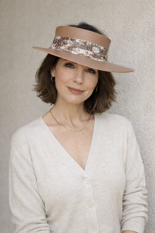 Woman wearing a beige visor hat with floral band against a neutral background