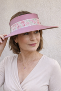 Woman wearing a pink visor with floral band against a light background