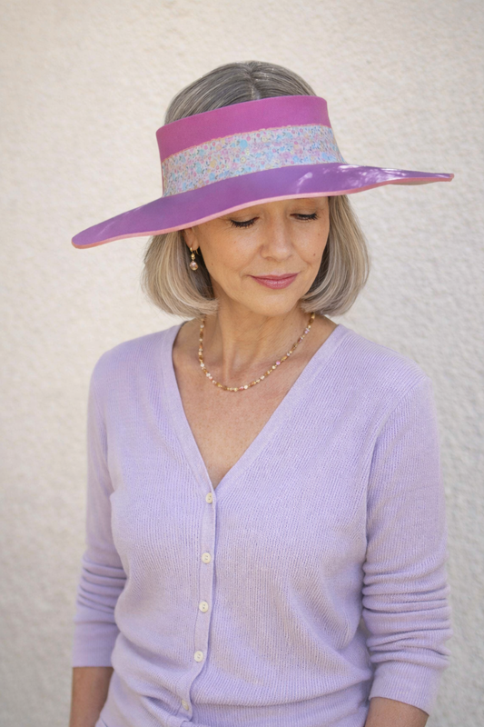Woman wearing a large purple visor against a plain background
