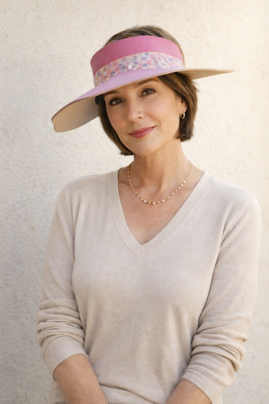 Woman wearing a wide-brimmed hat with a floral band against a plain background