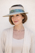 Woman wearing a wide-brimmed hat with a decorative band against a white background
