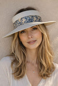 Woman wearing a wide-brimmed hat with floral band against a beige background