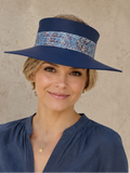 Woman wearing a blue visor hat with a floral band against a beige wall