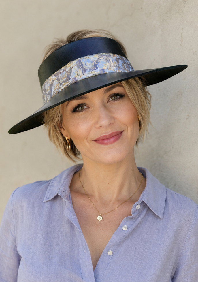 Woman wearing a wide-brimmed hat with floral band against a plain background