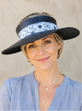 Woman wearing a wide-brimmed hat with a floral band against a neutral background