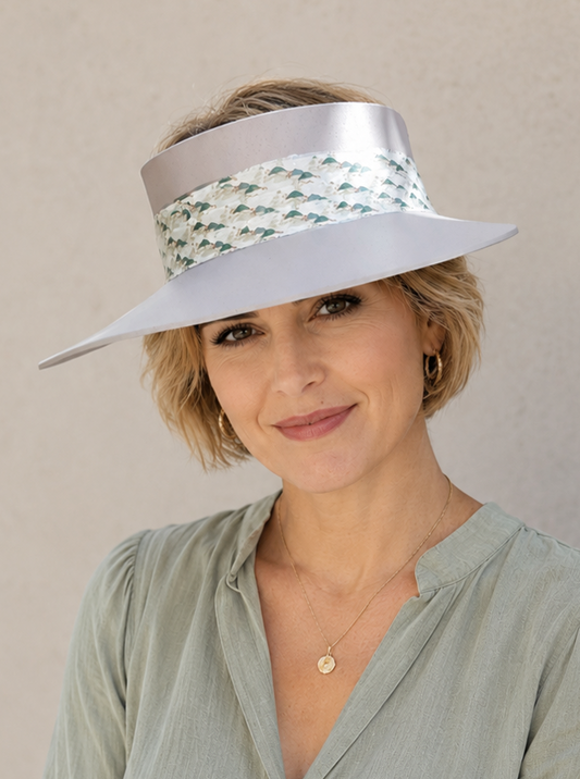 Woman wearing a light green shirt and a wide-brimmed hat with a decorative band against a beige background