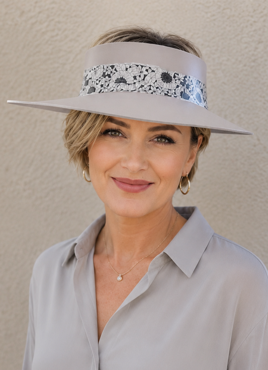 Woman wearing a light gray blouse and visor against a beige background