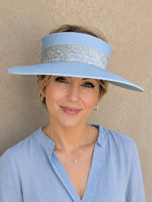 Woman wearing a light blue visor and matching blouse against a beige wall