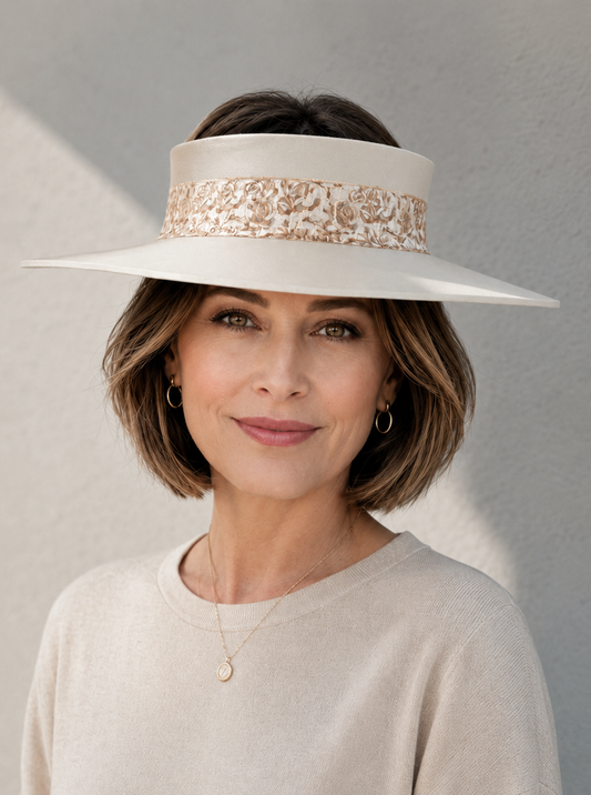 Woman wearing a white wide-brimmed hat with floral embellishments against a gray background