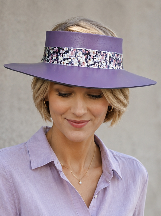 Woman wearing a purple hat with a decorative band and matching shirt against a plain background