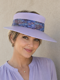 Woman wearing a light purple visor and matching blouse against a beige background