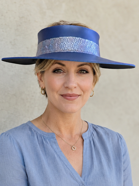 Woman wearing a blue hat with a decorative band against a plain background
