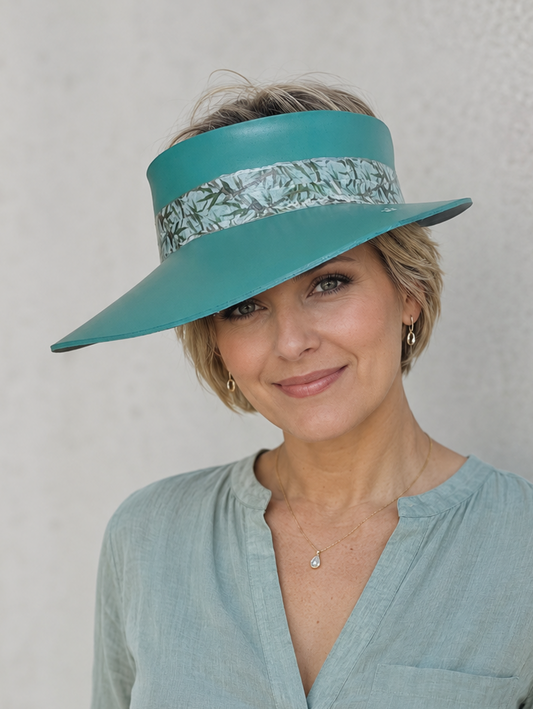 Woman wearing a teal visor with floral band against a plain background