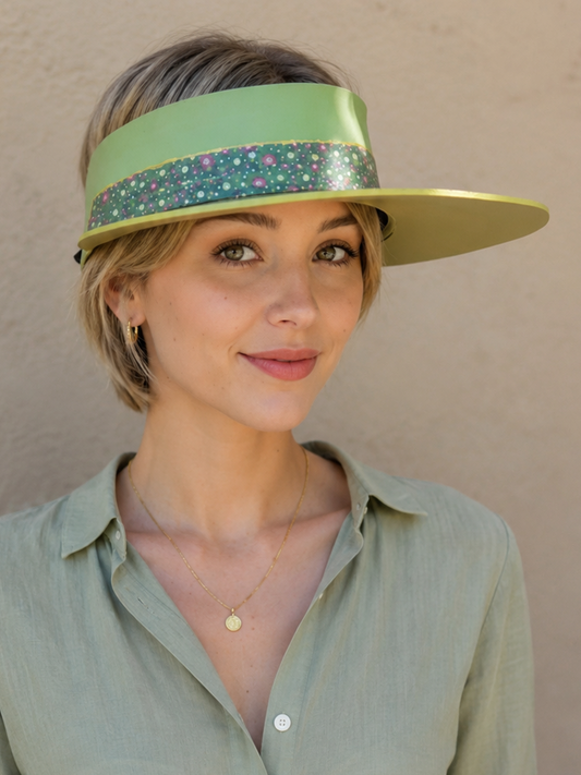 Woman wearing a green visor and matching shirt against a beige wall