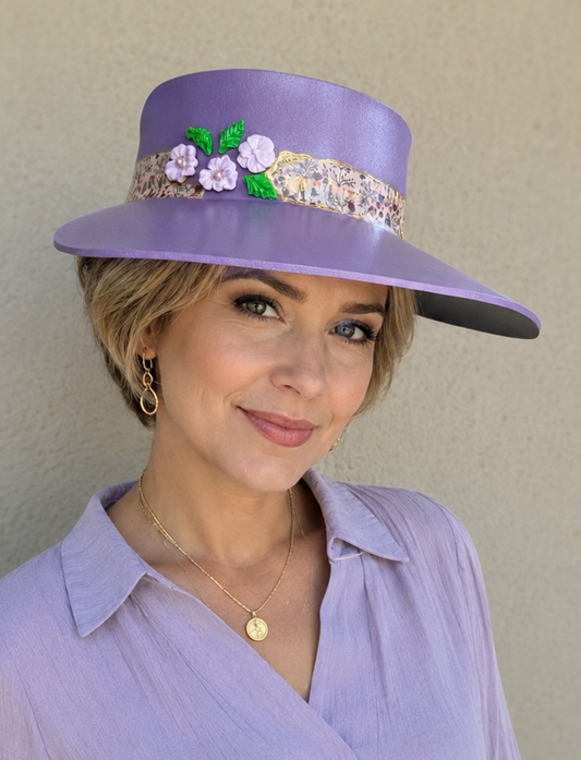 Woman wearing a purple hat with floral embellishments against a plain background