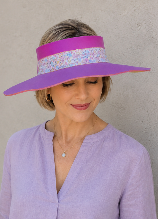 Woman wearing a purple visor with floral pattern against a plain background