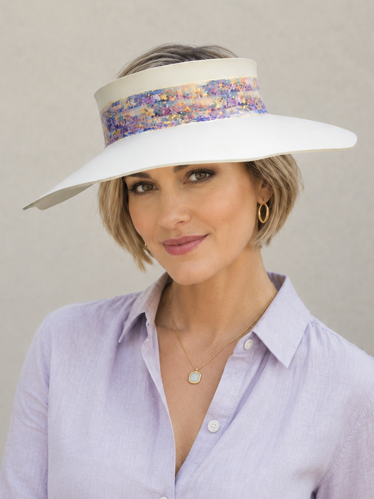Woman wearing a wide-brimmed hat with a colorful band against a neutral background