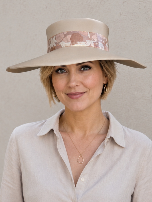 Woman wearing a wide-brimmed hat with floral band against a plain background