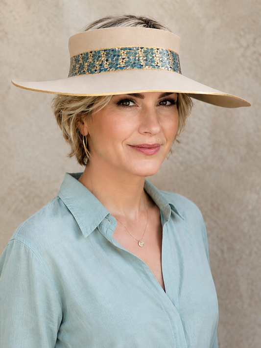 Woman wearing a wide-brimmed hat with a decorative band against a neutral background