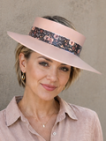 Woman wearing a wide-brimmed hat with a patterned band against a plain background