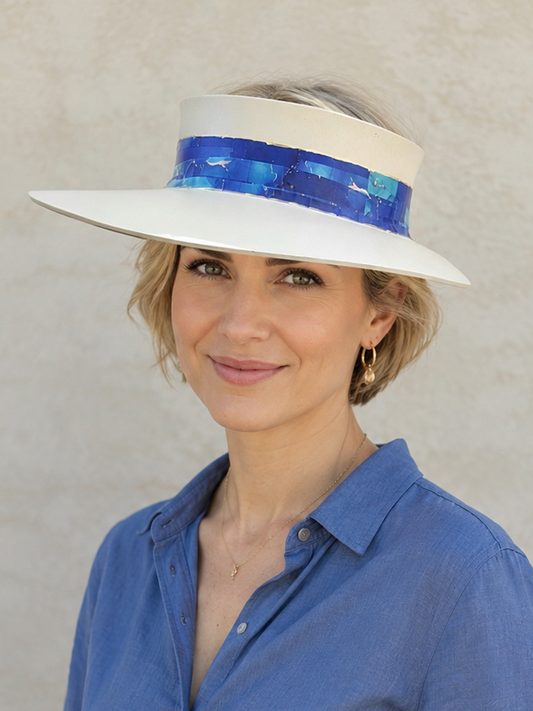 Woman wearing a white hat with a blue band and a blue shirt against a beige background