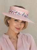 Woman wearing a pink visor with floral band against a beige background