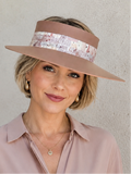 Woman wearing a wide-brimmed hat with a sequin band against a neutral background