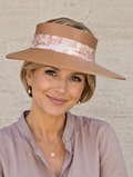 Woman wearing a beige visor hat with a pink band against a beige background