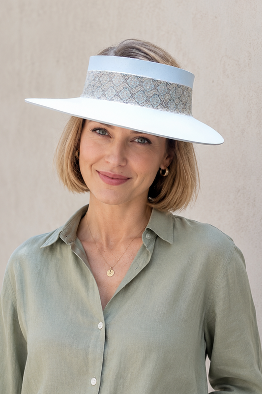 Woman wearing a white sun visor with a patterned band against a beige background