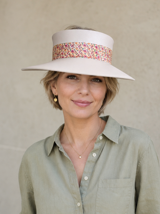 Woman wearing a wide-brimmed hat with a patterned band against a plain background