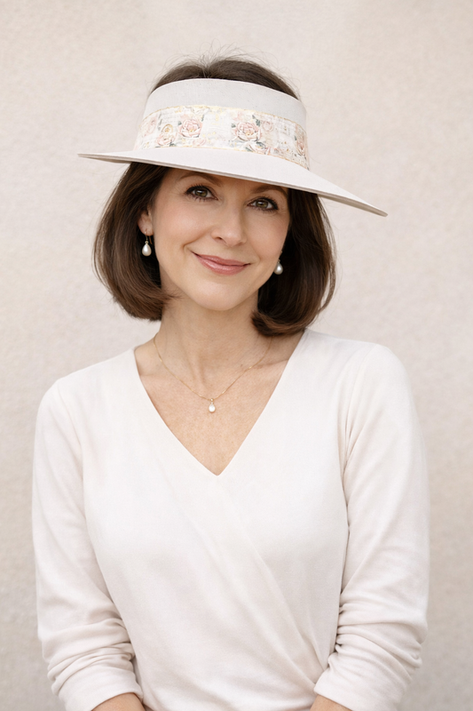 Woman wearing a white visor with floral details on a plain background